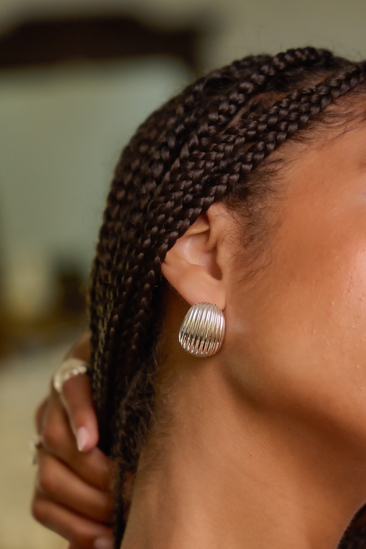 Model wearing silver Florence ribbed hoop earring with hand resting behind the head.