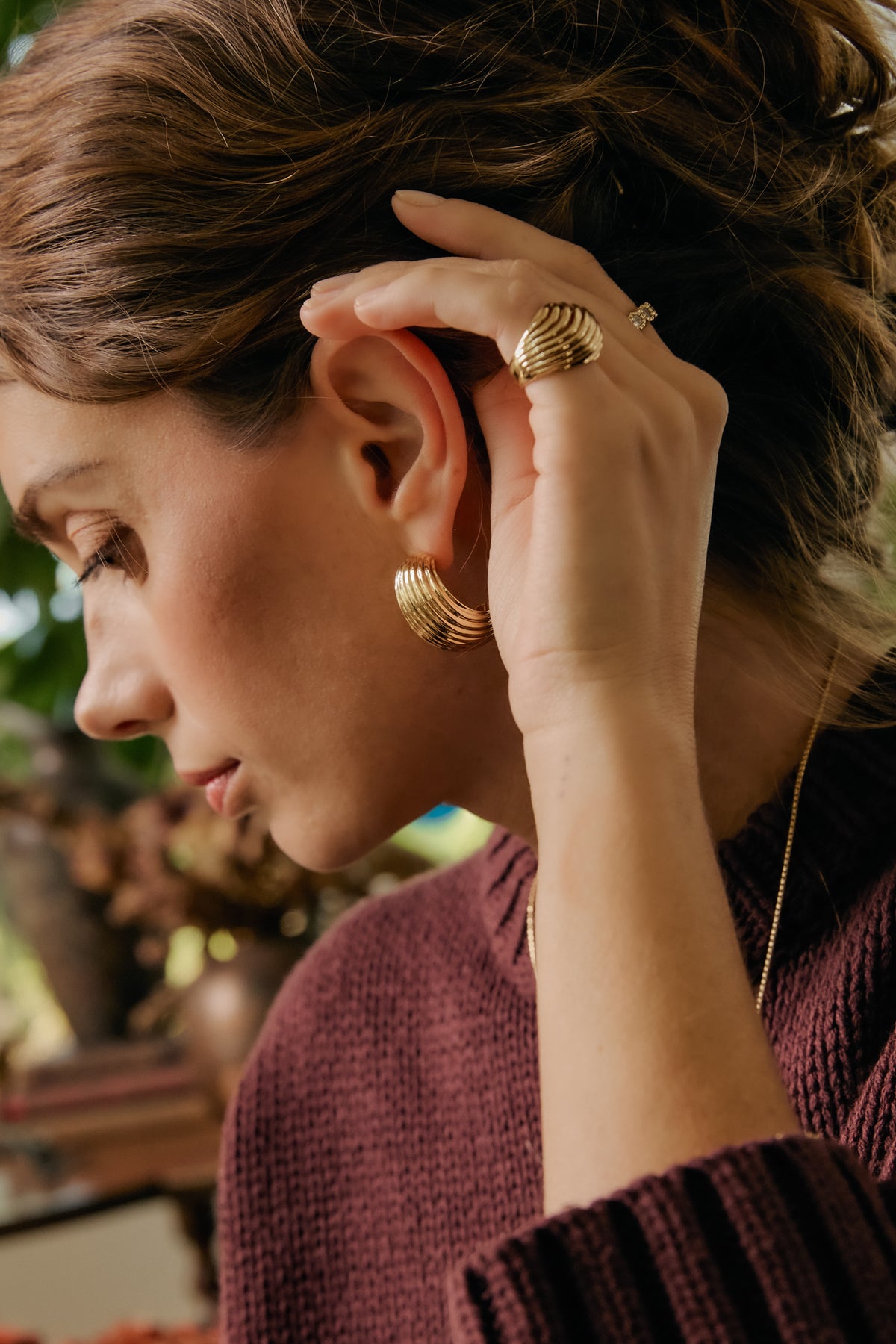 Model wearing gold Florence ribbed dome earring and gold Etta dome ring, styled with a burgundy sweater.