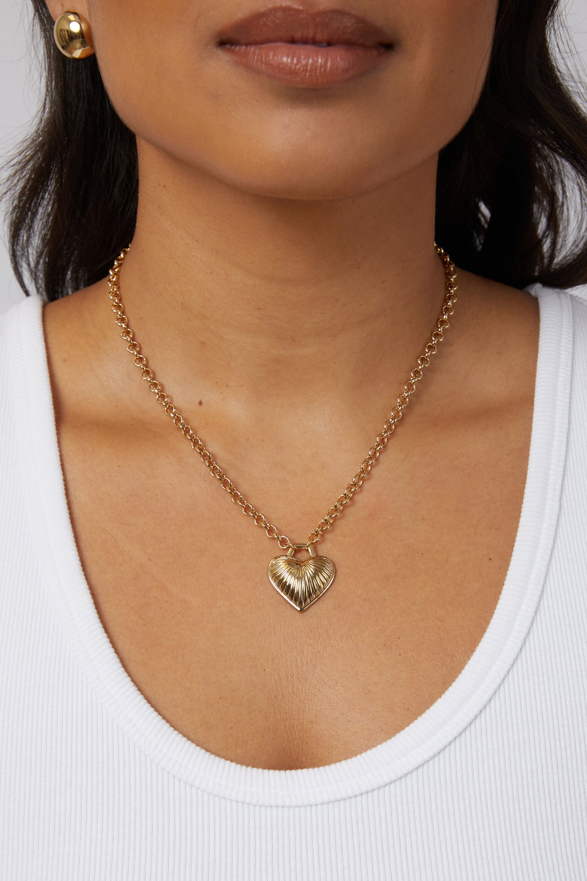 Model wearing the gold Juliet heart pendant necklace styled on a lower chest neckline.