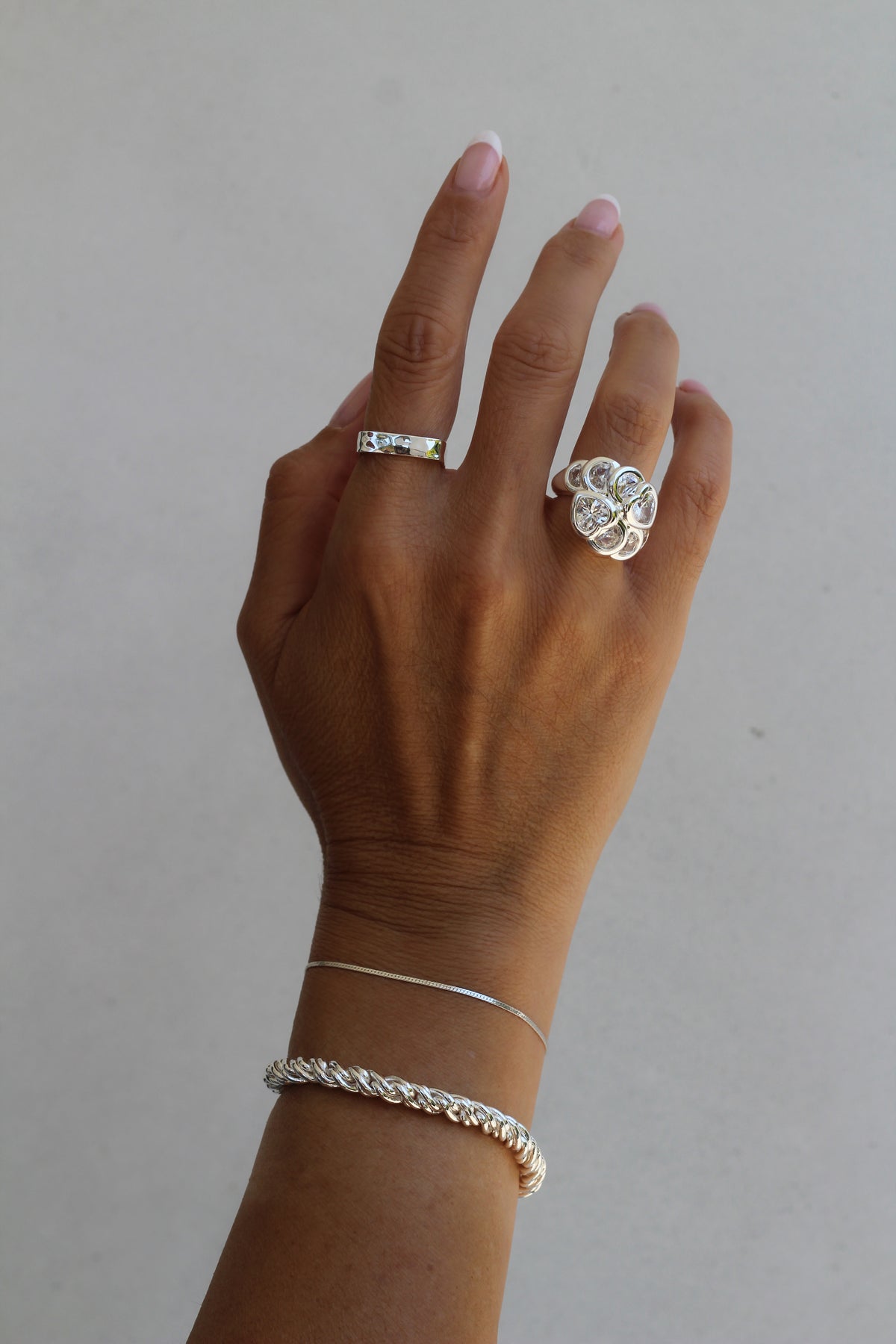 Close-up of a model's wrist wearing the sterling silver Josephine and Adriana bracelets paired with the Bardot and Mae ring.
