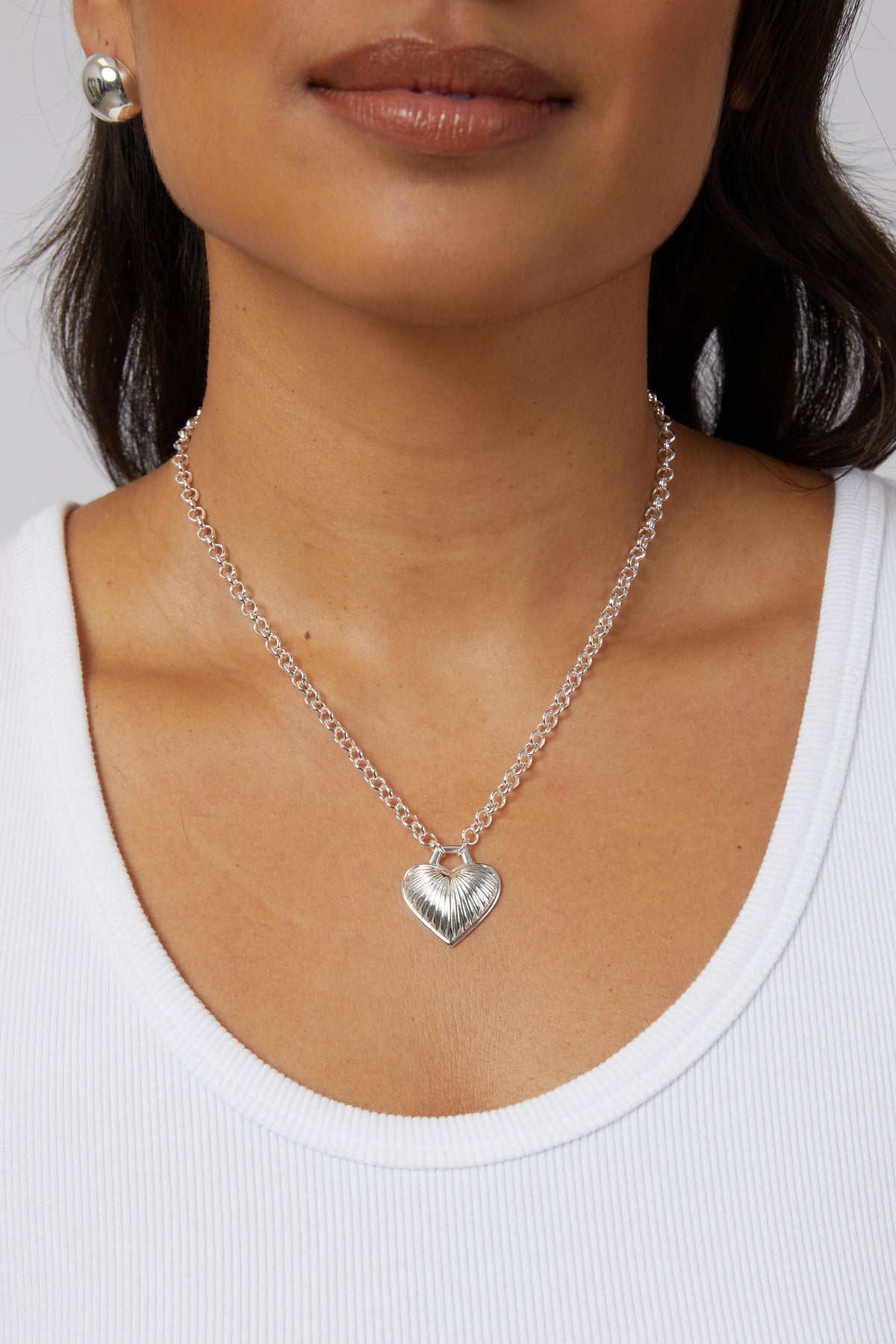 Model wearing the silver Juliet heart pendant necklace styled lower on her chest.