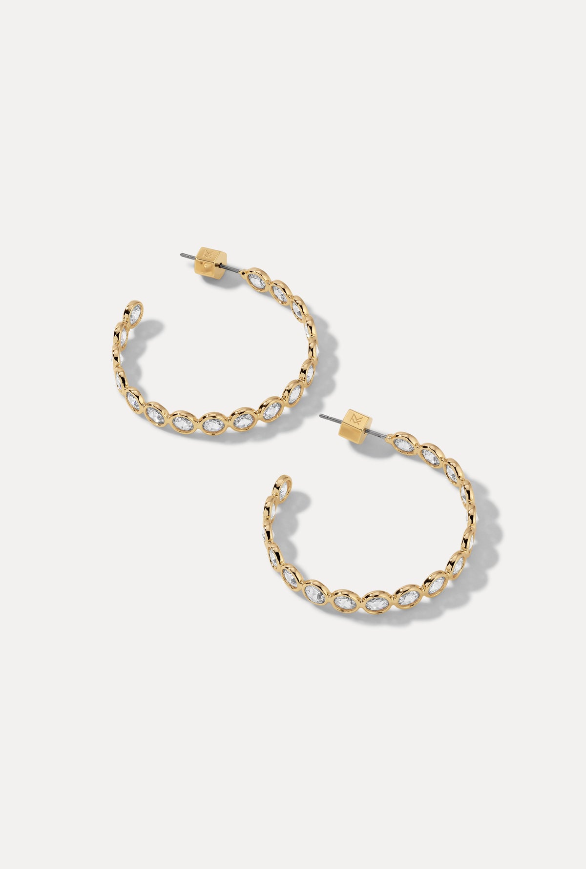 Pair of gold Lynda Hoops with bezel-set cubic zirconia stones on white background.