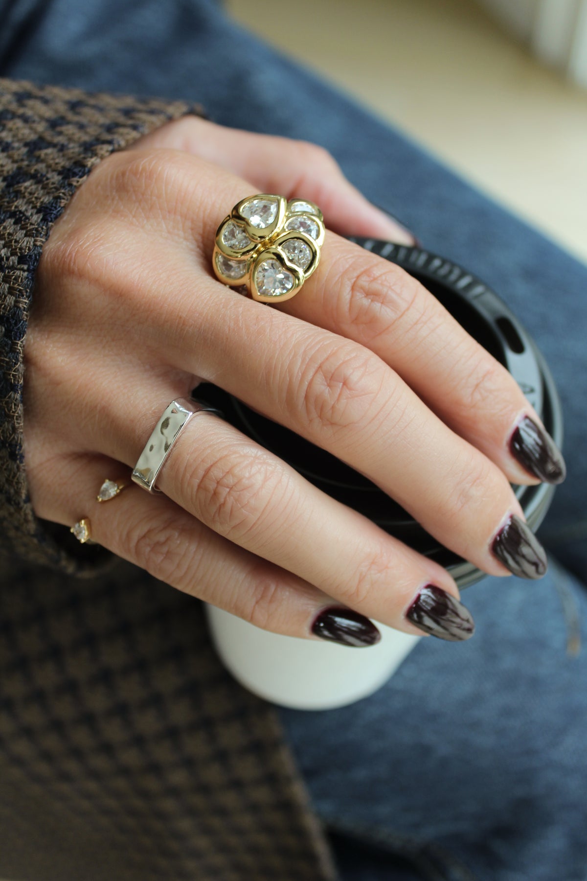 Up close image of a model's hand wearing the Bardot ring in gold and Mae ring in silver. 