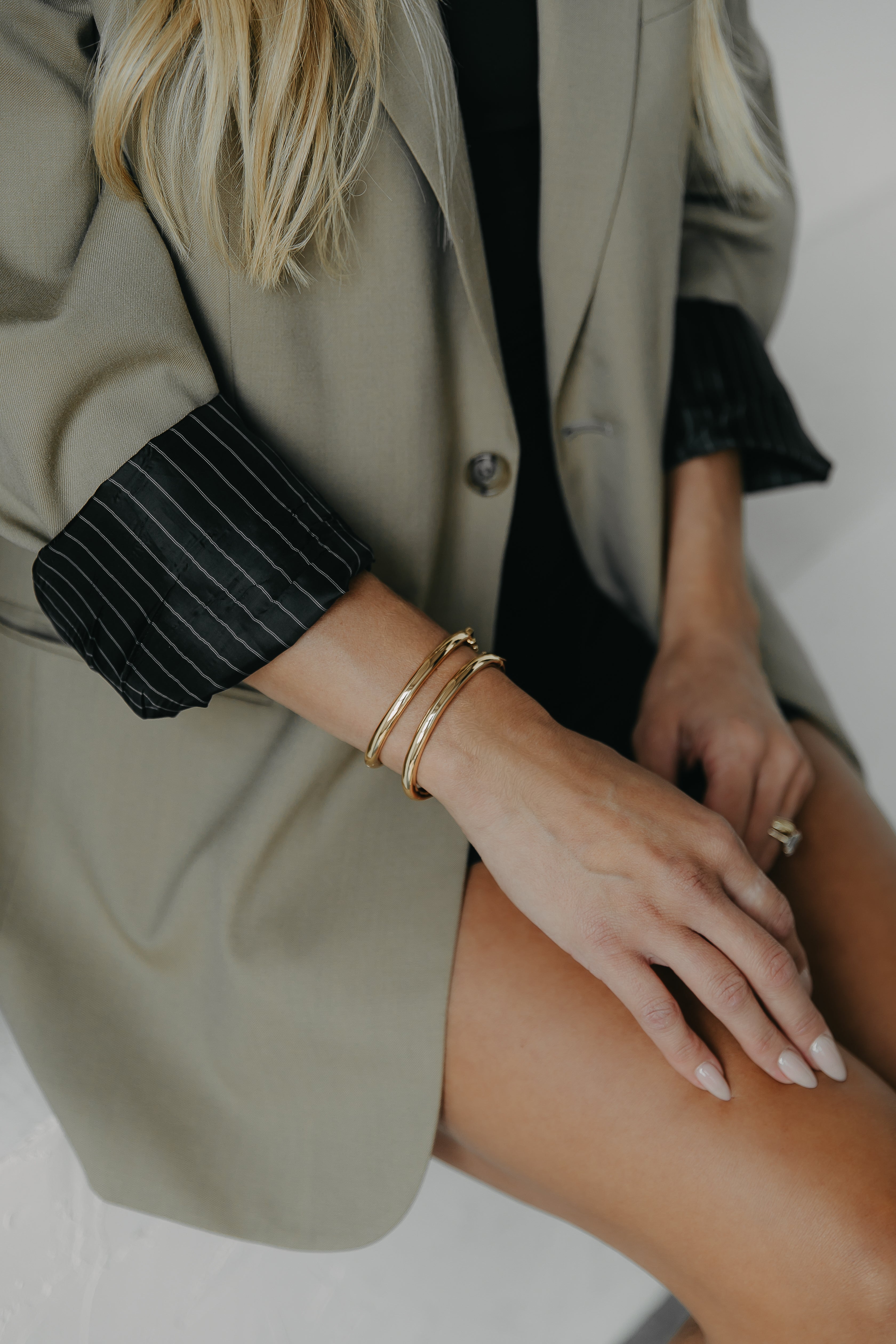 Image of Influencer Mina wearing two Mina Cuffs in gold with a beige blouse.