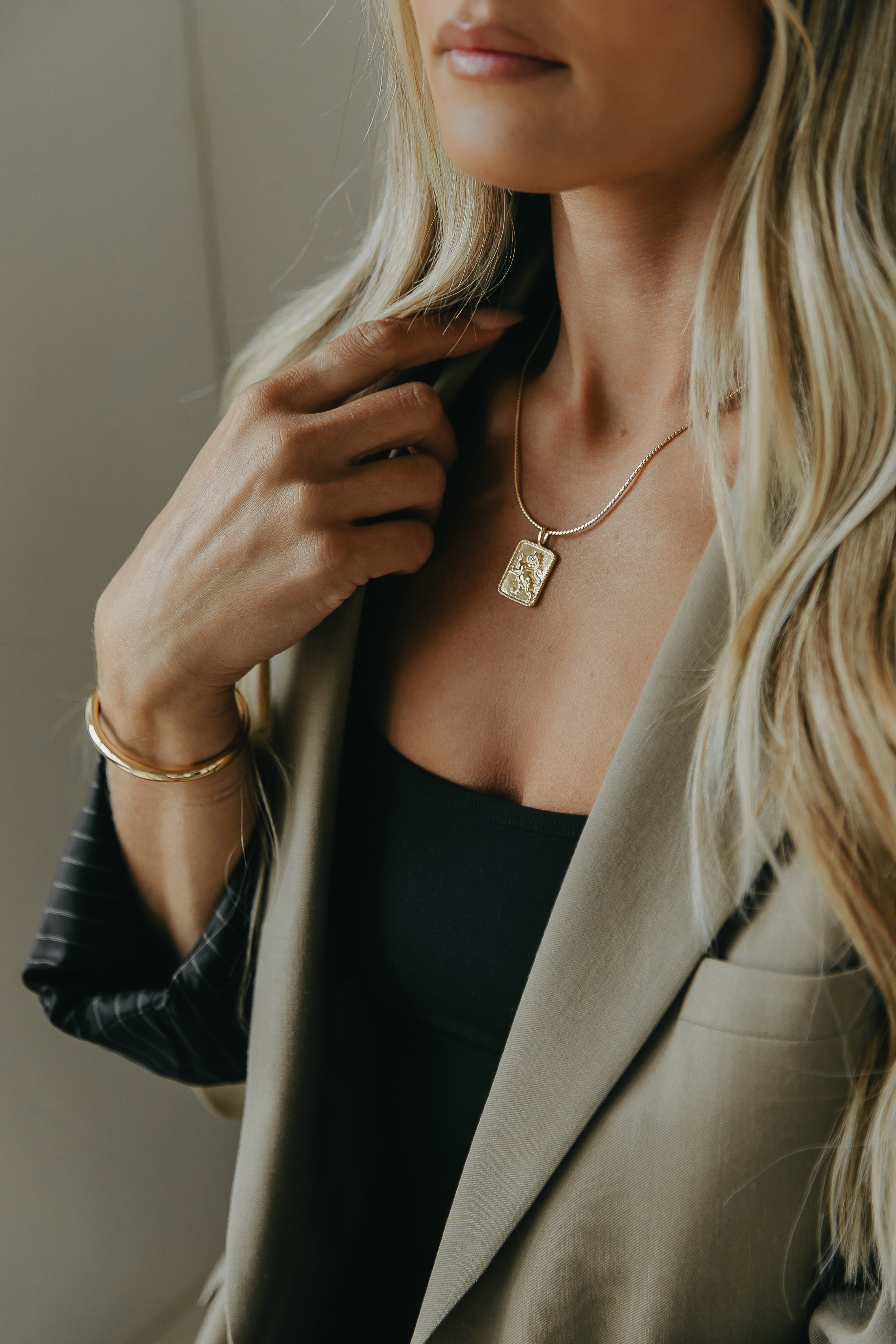 Influencer Mina wearing a gold filled chain and gold love charm with a beige blouse.
