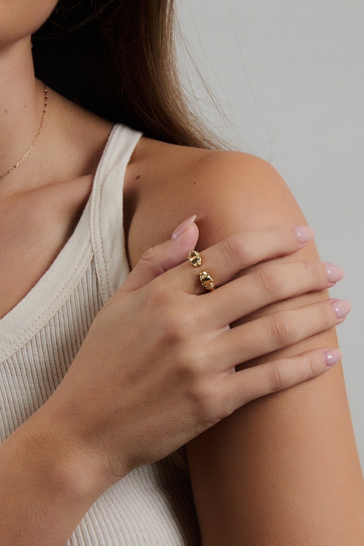 Model wearing gold Panther Ring on index finger, resting hand on shoulder in a cream ribbed top.