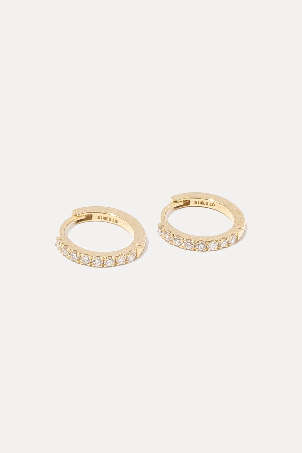 Pair of gold pavé diamond huggie hoop earrings displayed against a plain white background.