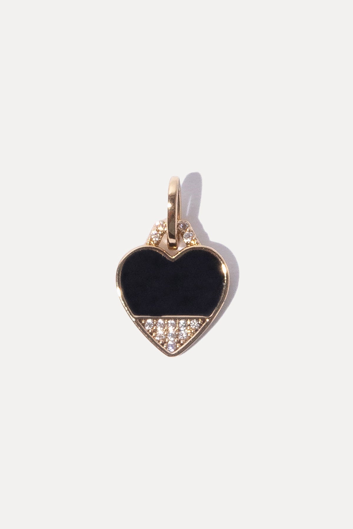 Gold heart charm filled with black enamel and a sparkling clear stone against a plain white background.