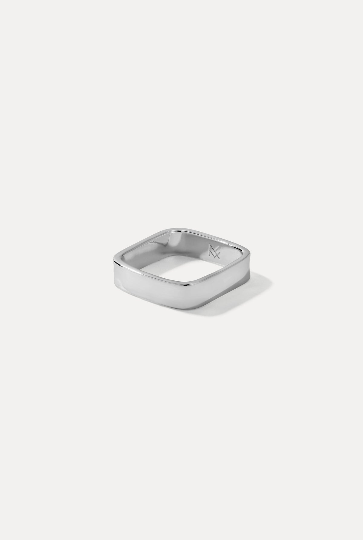 A polished silver-toned metal ring with a rounded square shape, shown on a clean, light gray background with a soft shadow.