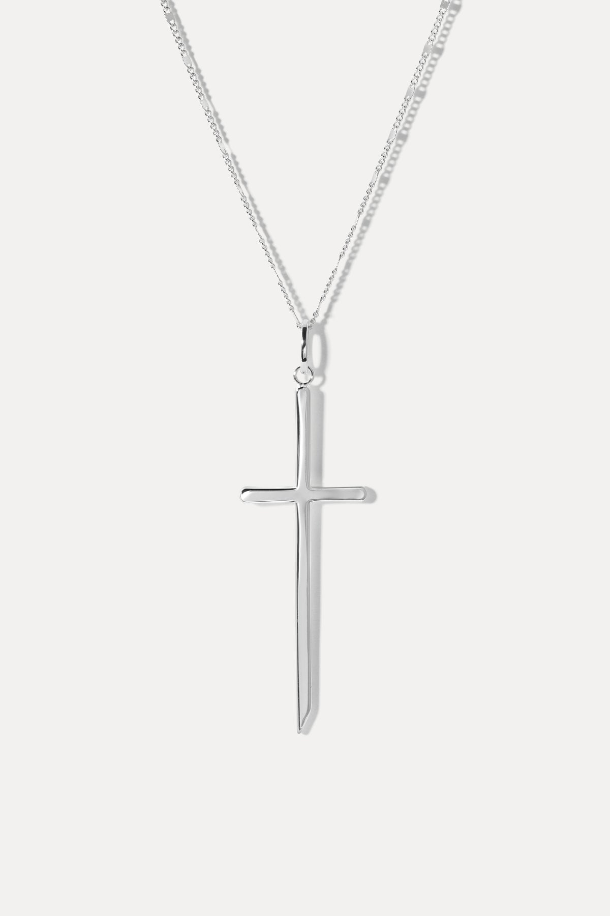 Silver cross pendant attached to a silver chain necklace displayed against a plain white background.
