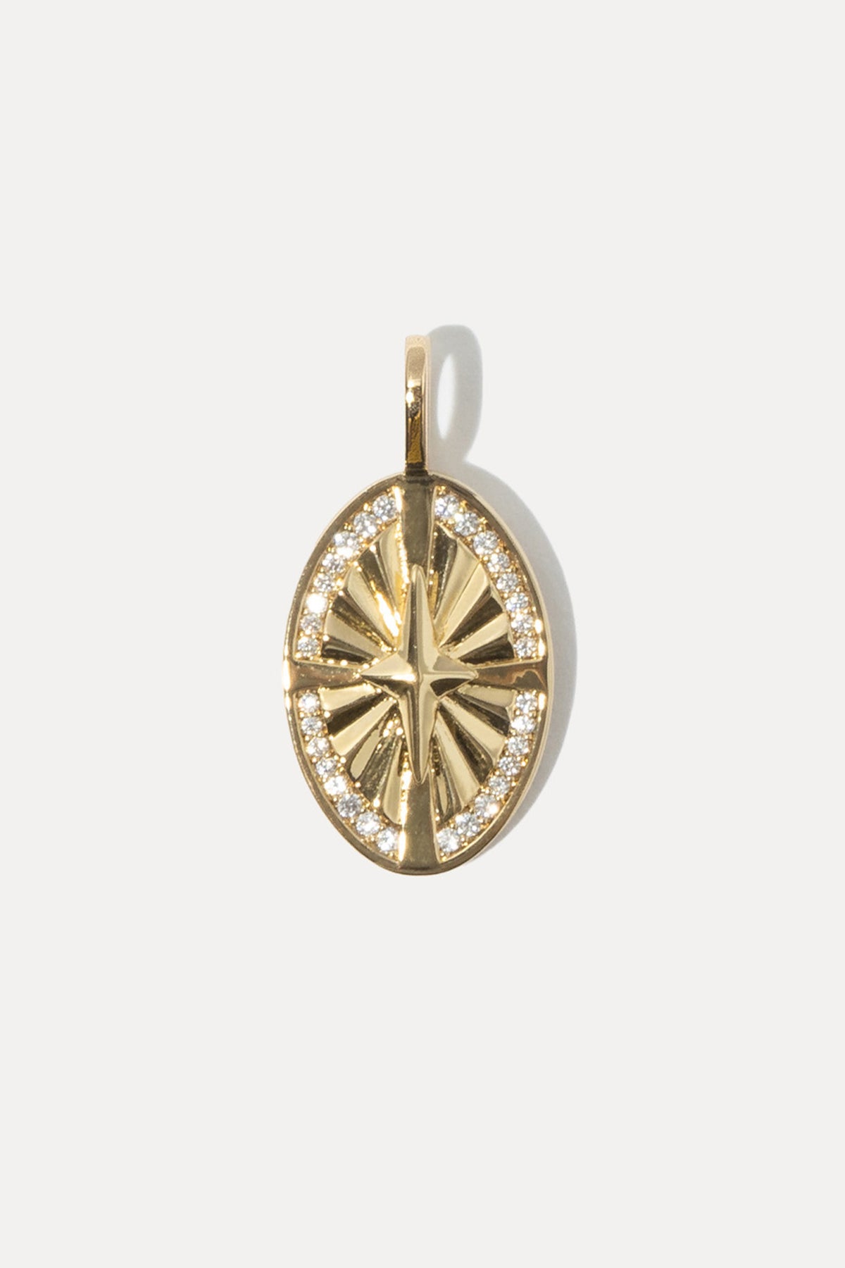 Gold compass medallion charm with clear cubic zirconia stones set on a standard bail against white background.