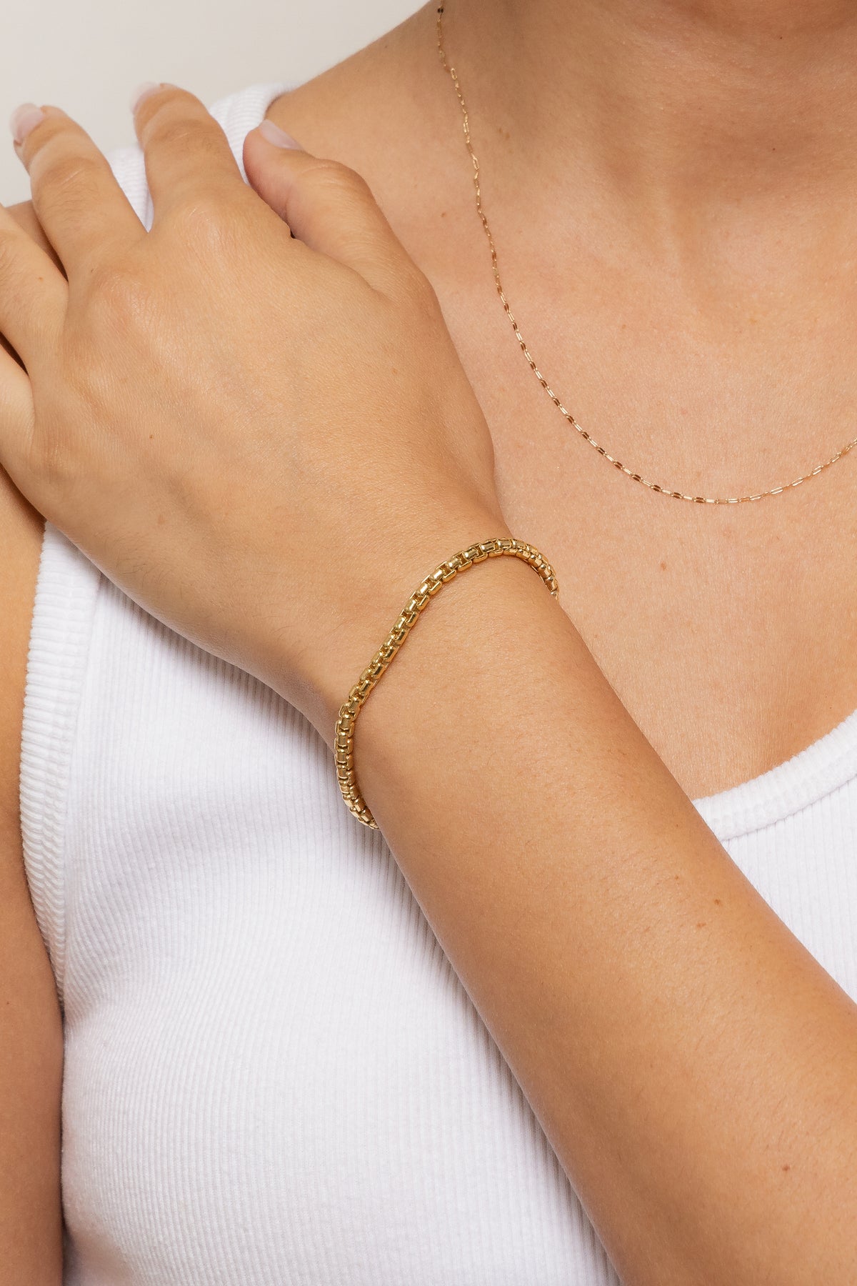 Close-up image of a model wearing a gold filled Wellon bracelet on her wrist.