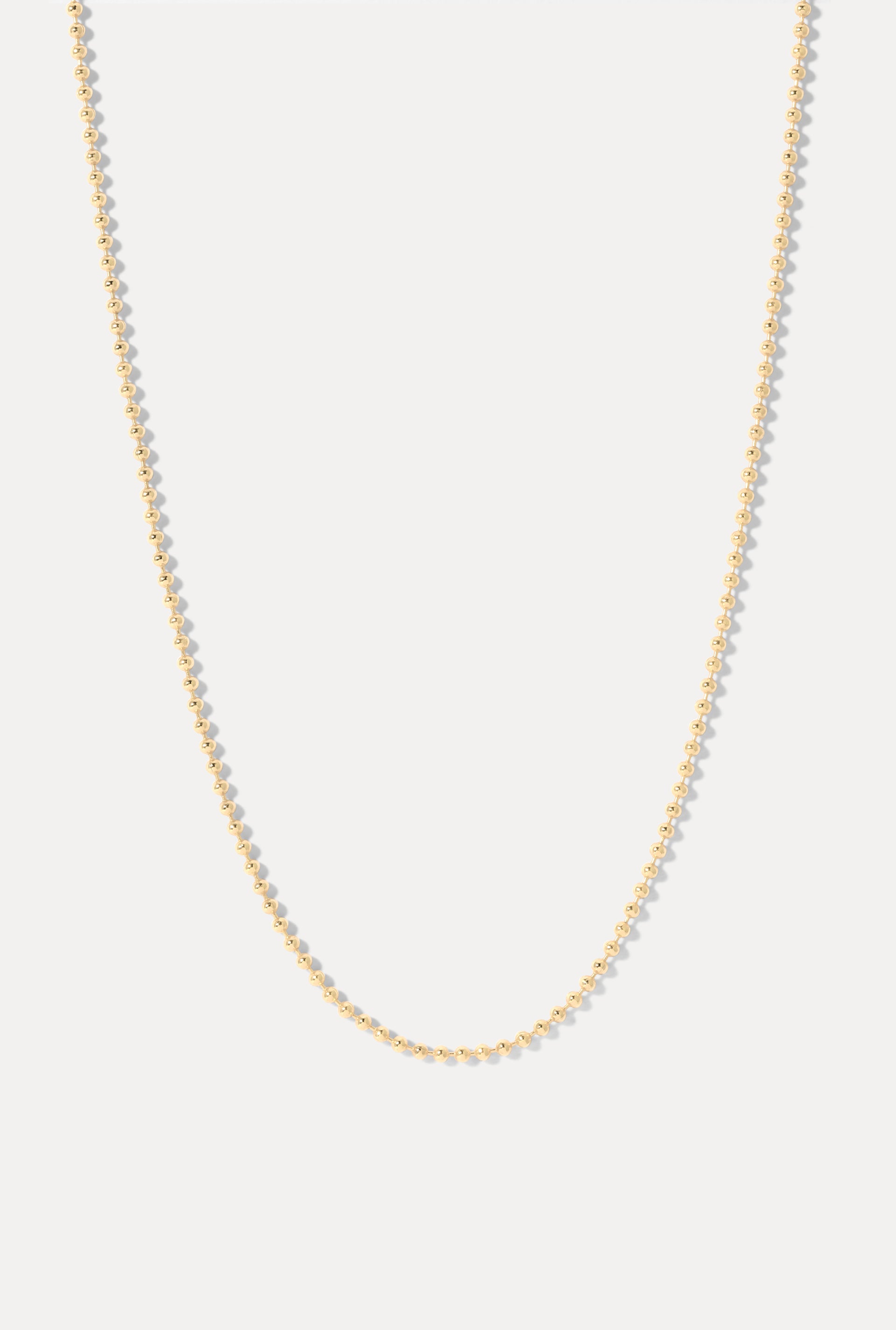 Long gold Whitney continuous ball chain necklace displayed in a U-shape on a white background.