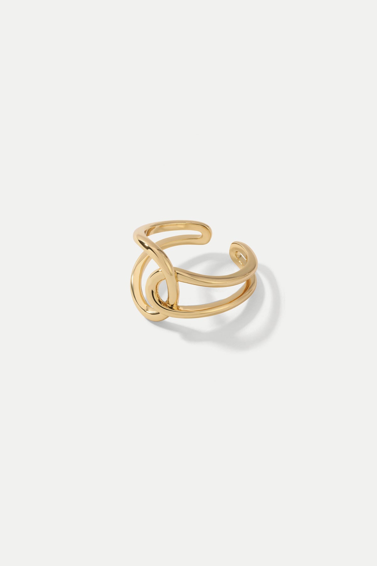 Gold Celine open band ring with a sculptural intertwined loop design featured on a white backdrop.
