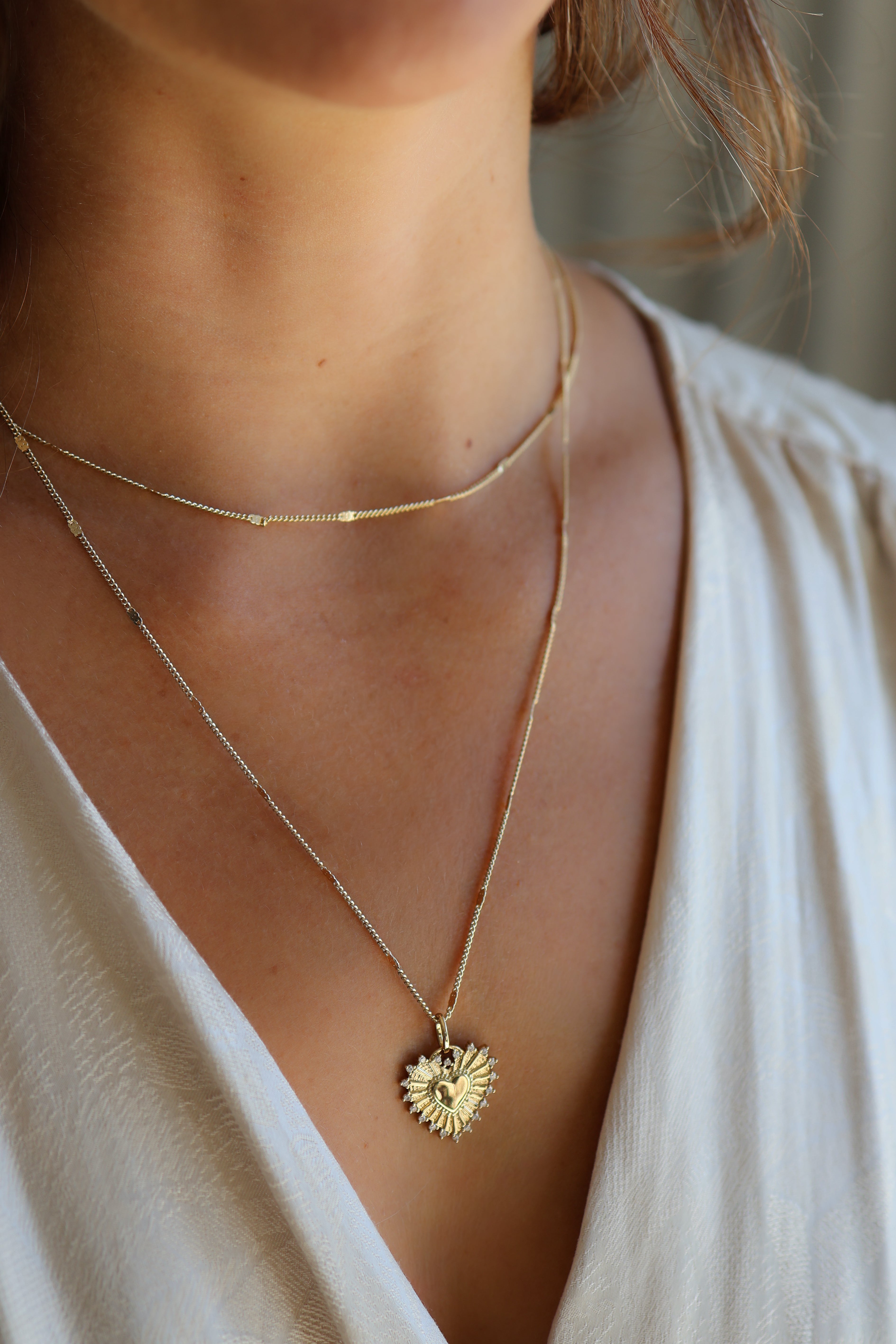 Model wearing the gold Coco chain and adorn charm layered wround the neck and upper chest.