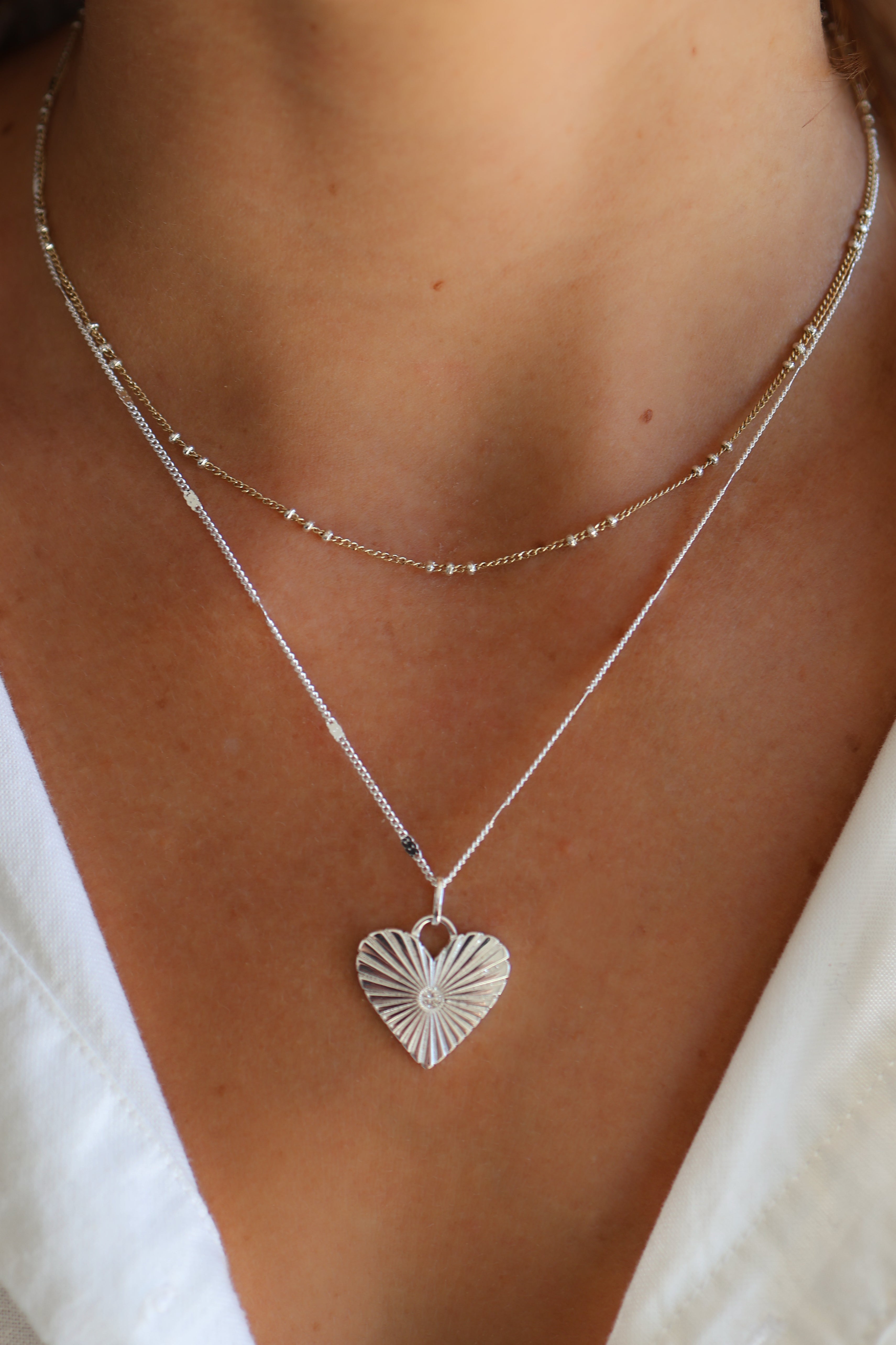 Model wearing the Coco chain in silver paired with the Eleanor charm and poppy chain.
