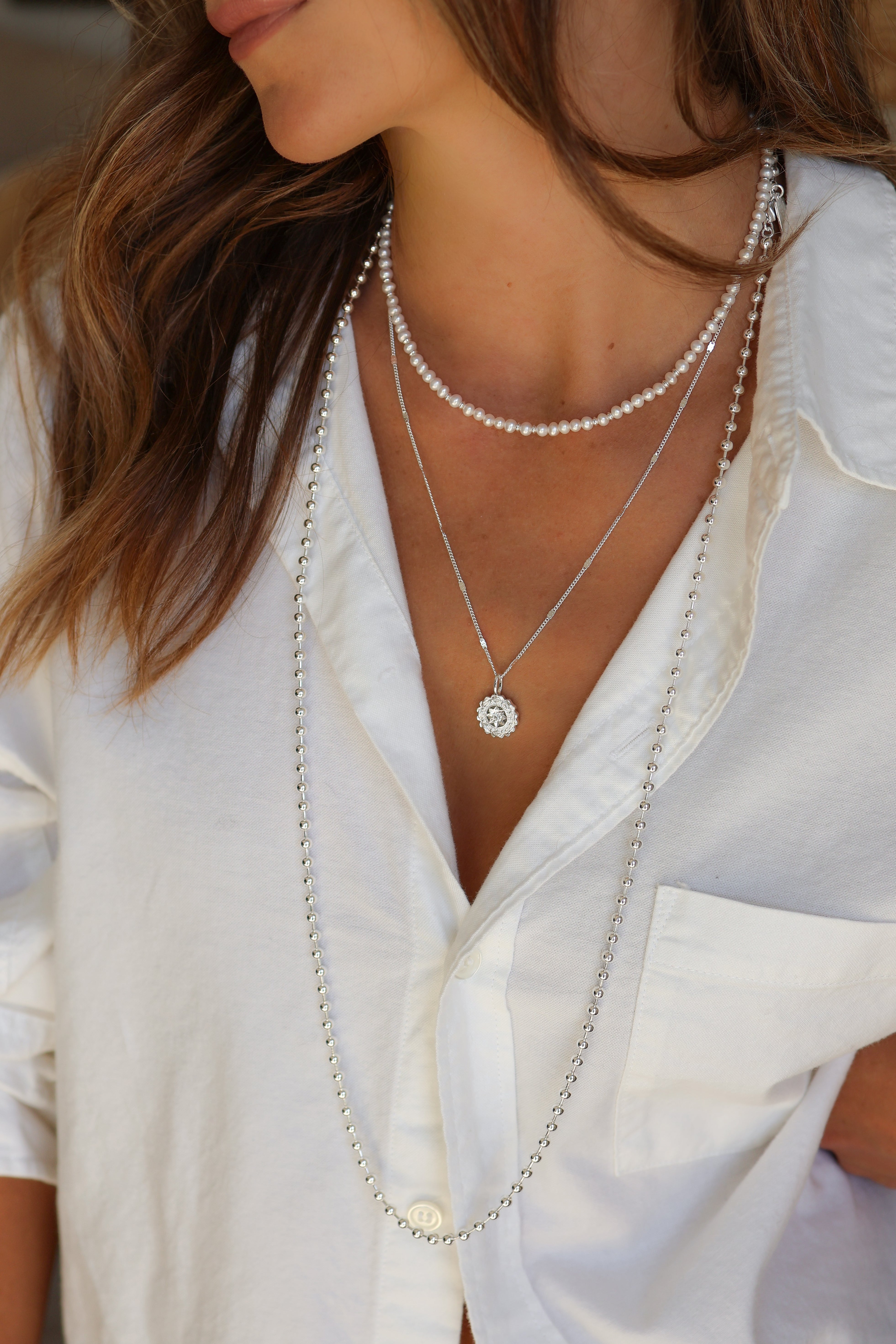 Model wearing the silver Coco Chain styled with the adorn heart charm and layered with the amelia and bette necklaces.
