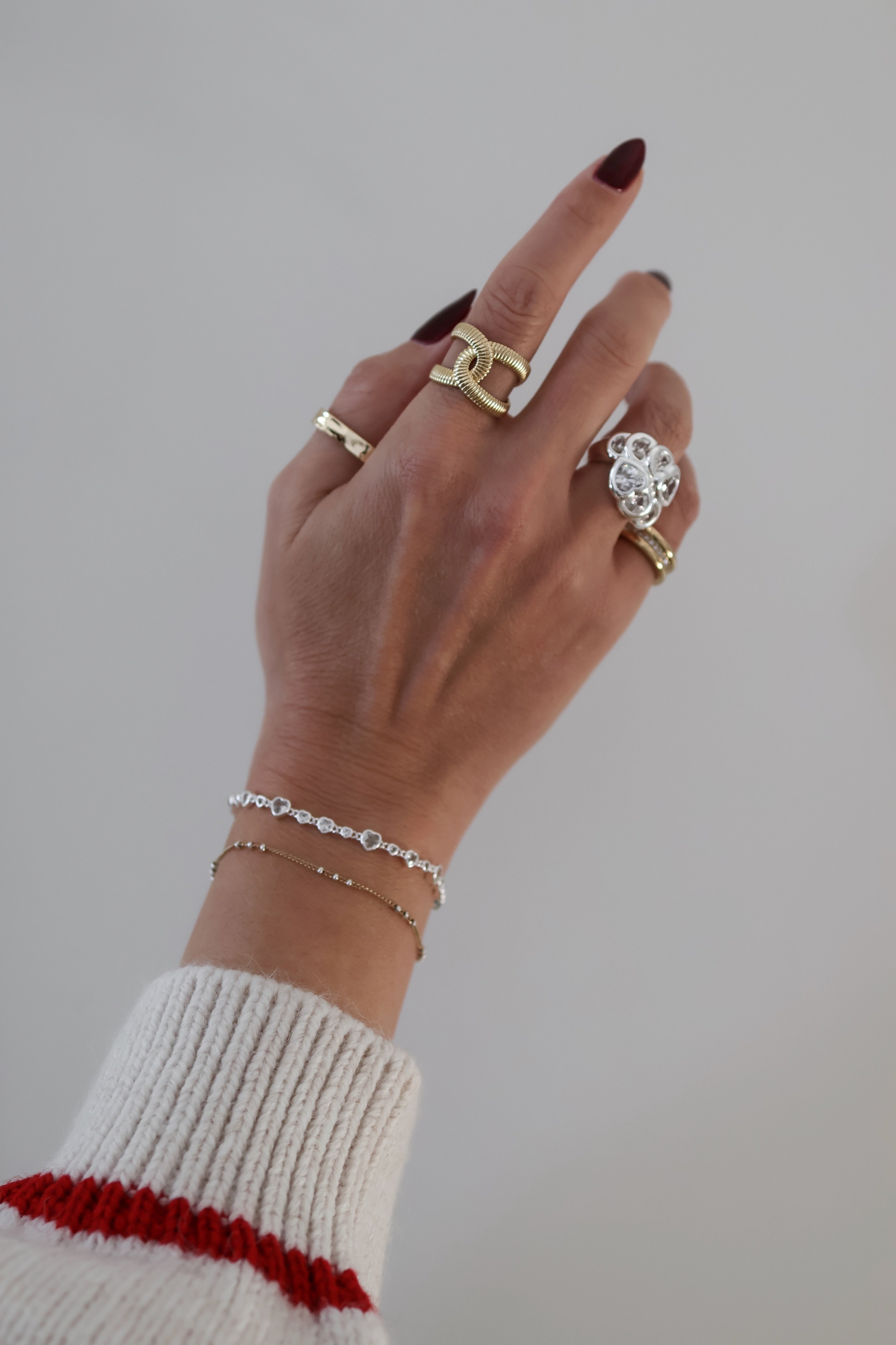 Models wrist showing the silver Cora bracelet paired with the Lisa and Bardot rings in gold.