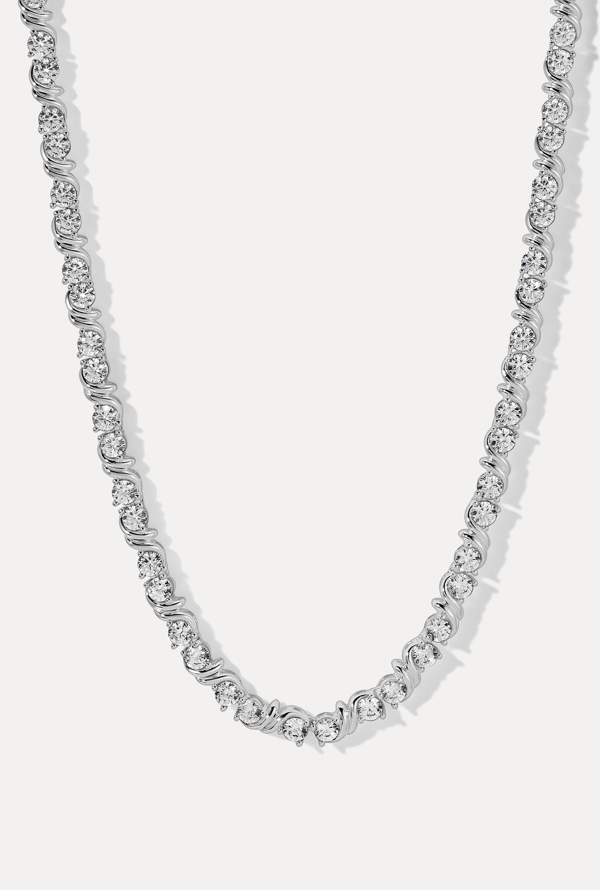 Silver Delilah tennis necklace featuring round CZ stones in S-link wave settings on a white background.
