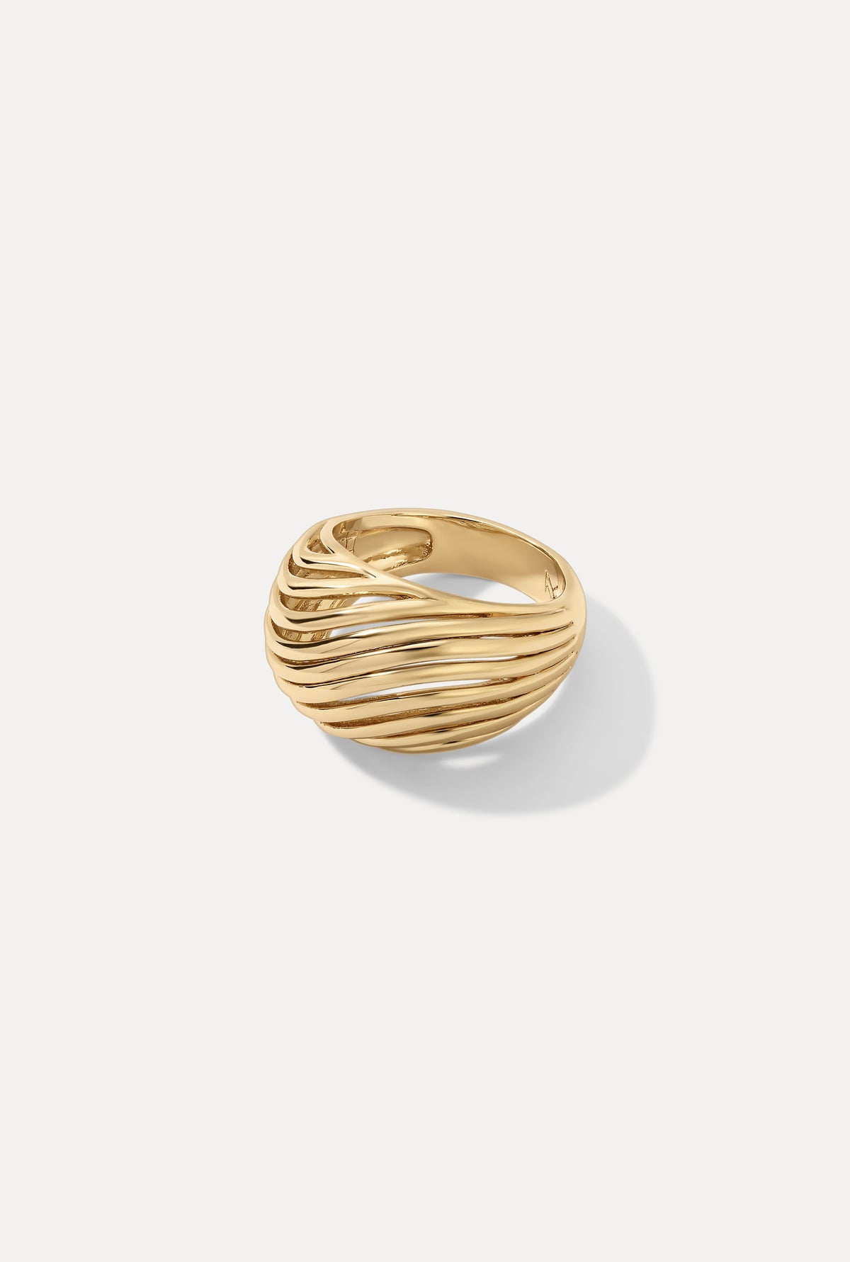 Gold Etta dome ring featuring a wide band with a sculpted, openwork wavy design on a white backdrop.