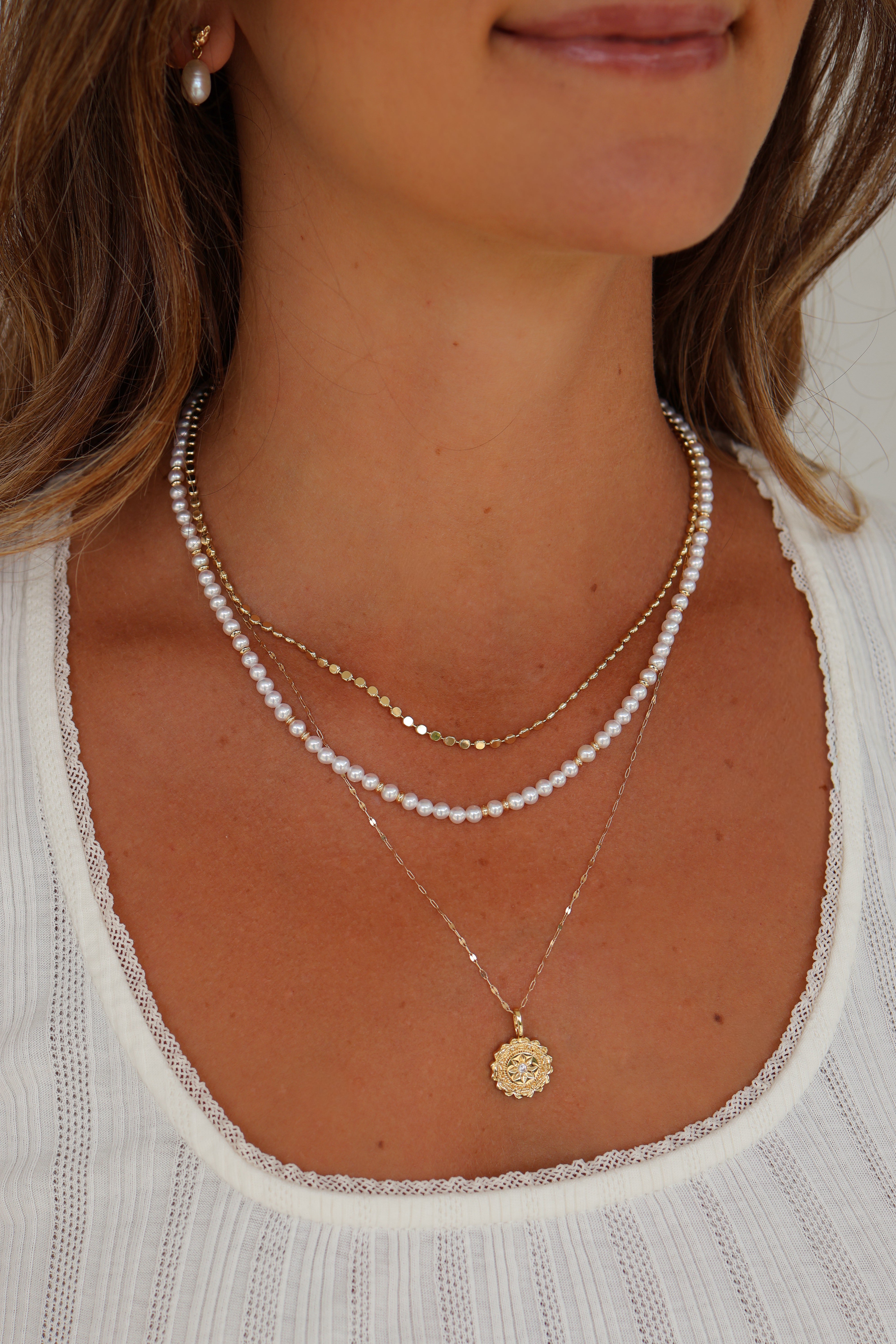Model photo showing the Bette Gold Pearl Necklace, paisley necklace, nora chain and Fleur charm.