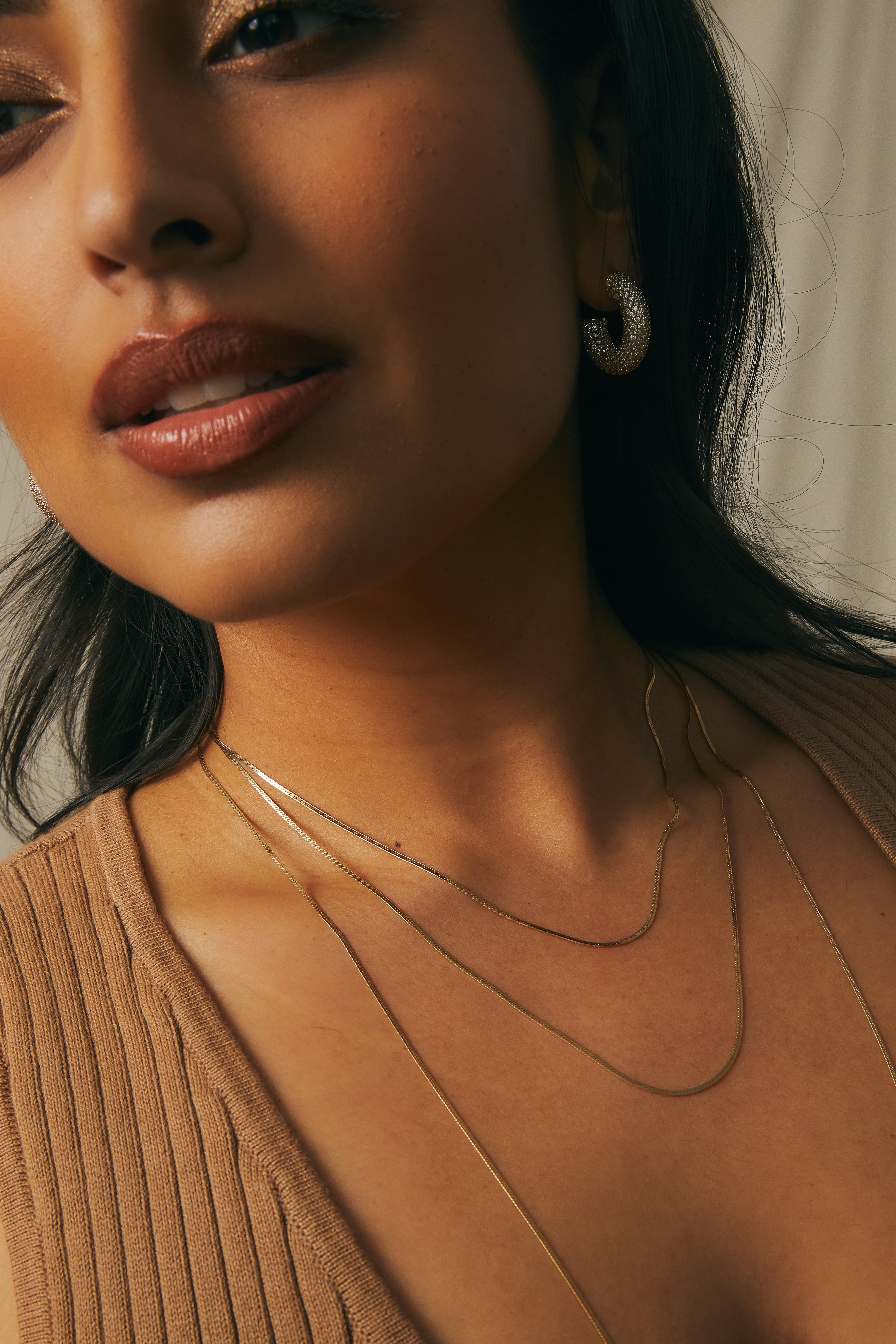 Close-up of a model wearing the gold Josephine Chain herringbone necklace in three sizes.