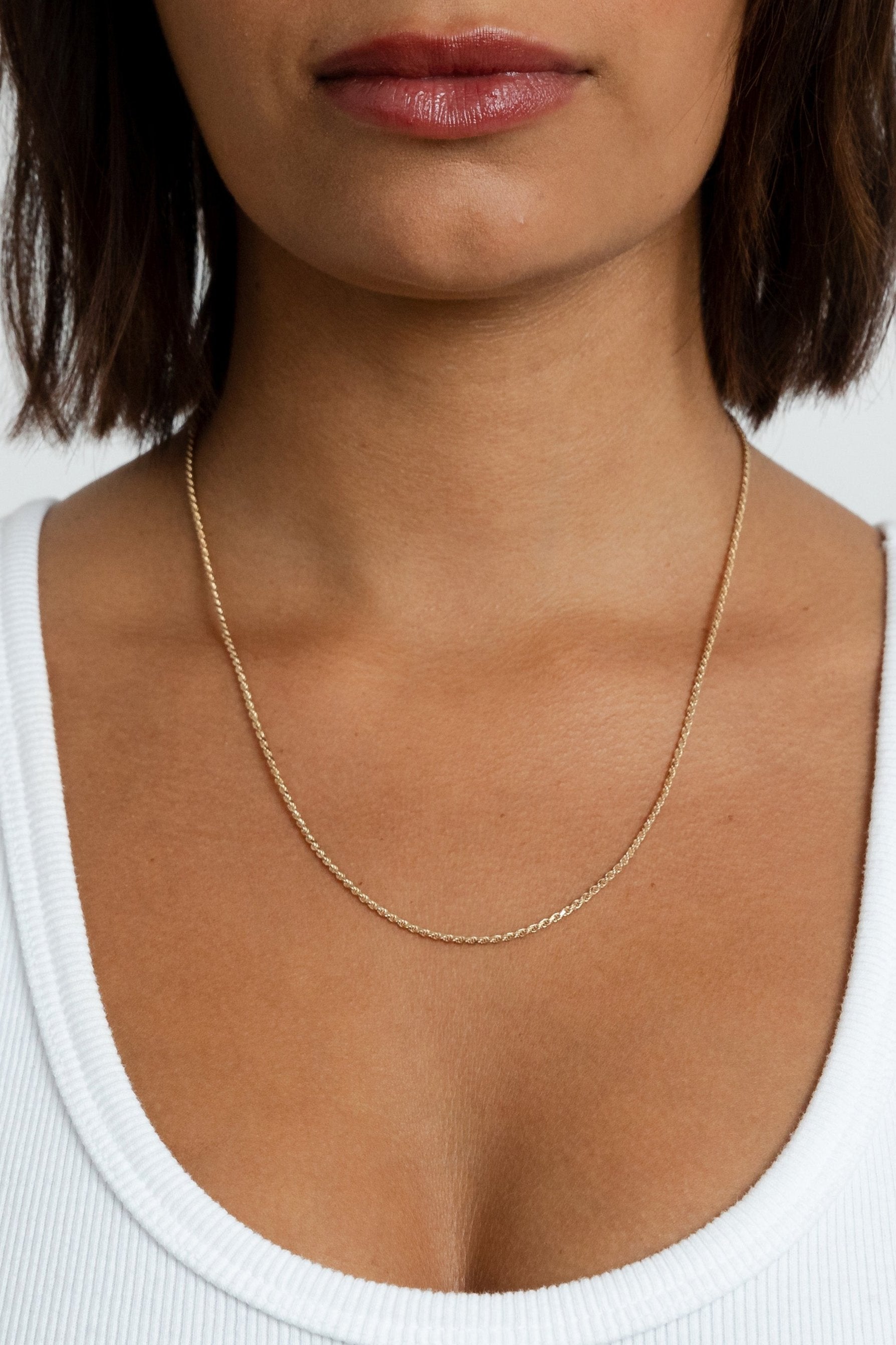 Model showcasing the gold Kate Chain rope necklace resting lower on her neckline.