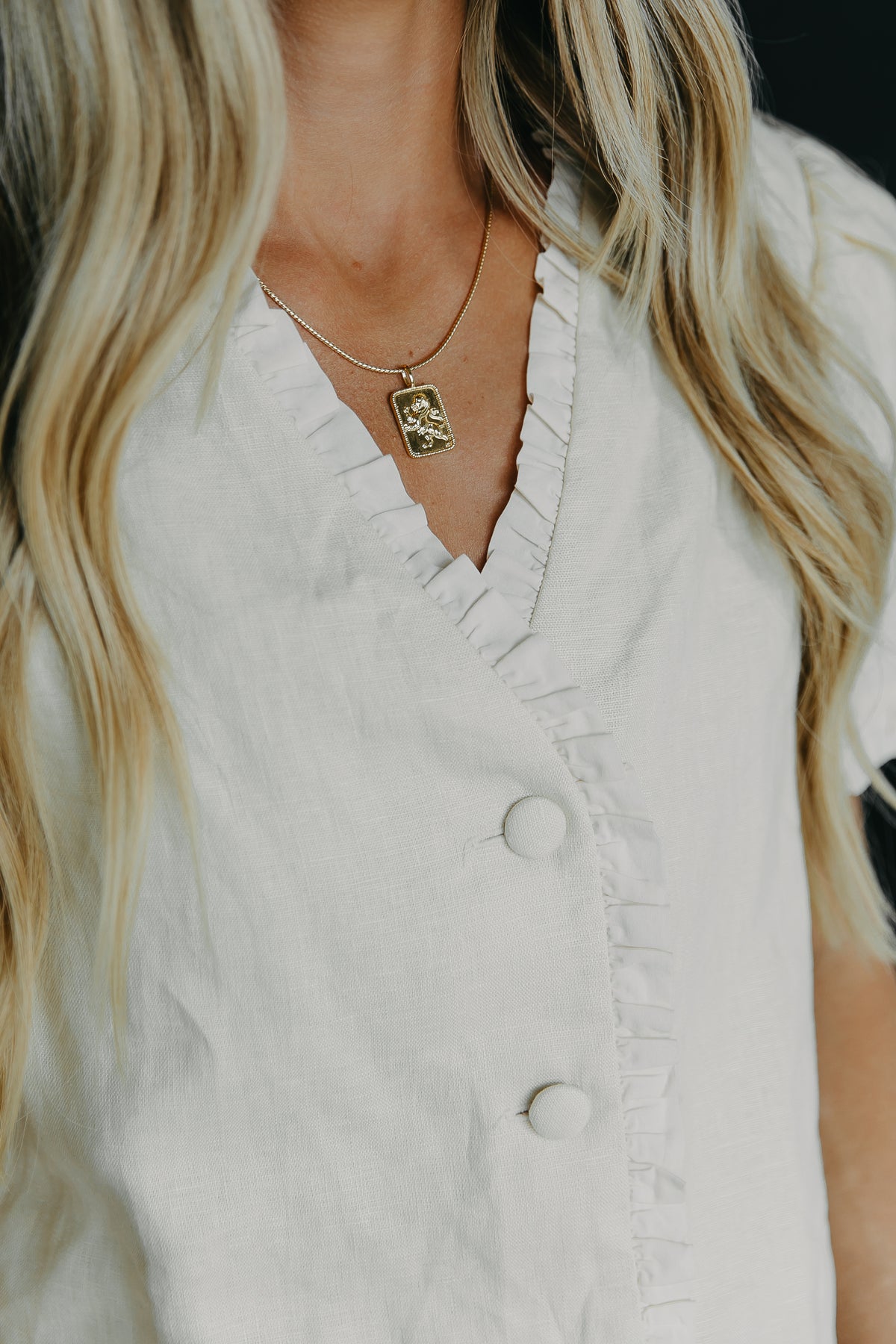Influencer Mina Zalyashko showcasing her name sake Mina chain and Lev charm with a white blouse.