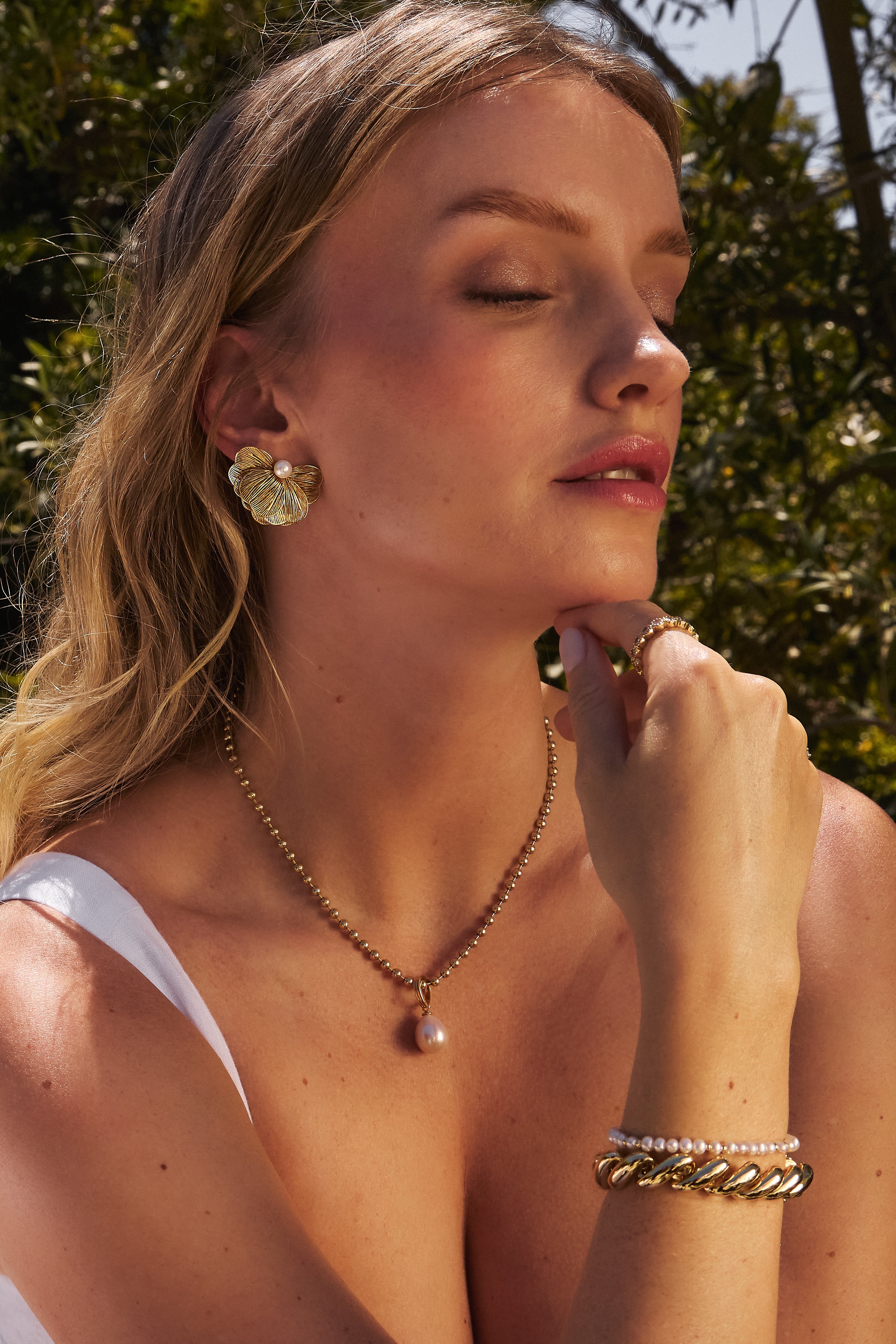 Close-up model photo of a woman wearing the Amelia Gold Ball Chain Necklace layered with the Perla charm.