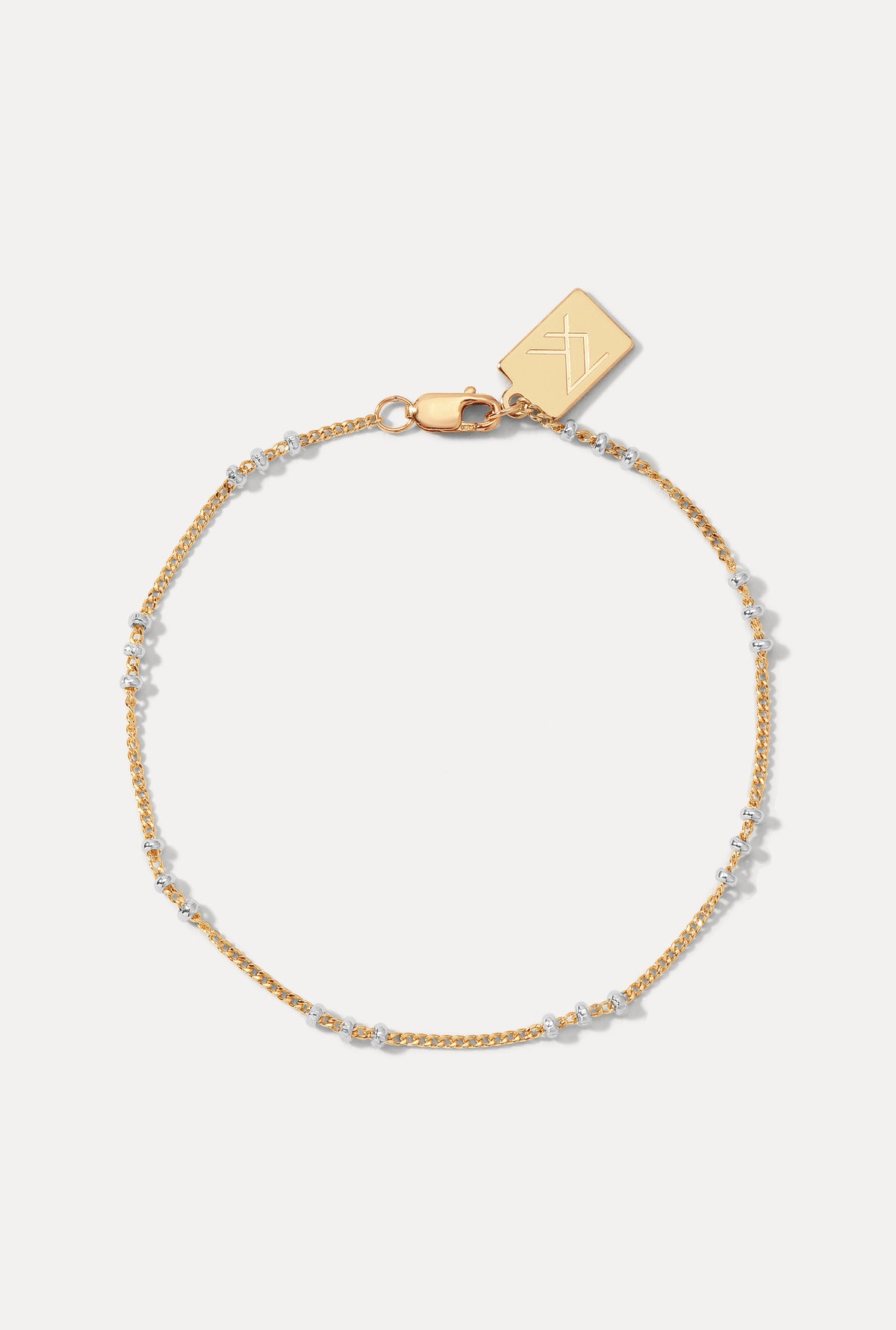 Gold satellite chain anklet with small silver accent beads displayed against a plain white background.