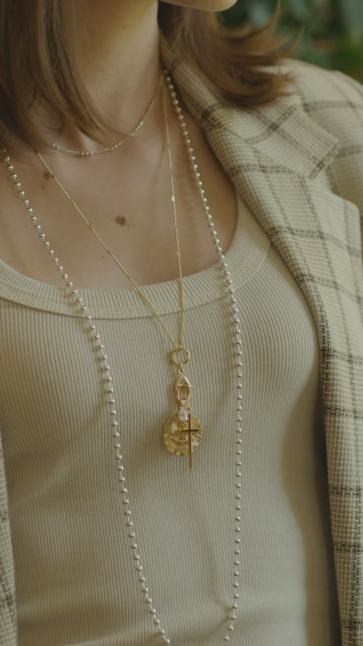 Model wearing the coco gold cable chain necklace and love charm alongside the Amelia silver necklace.