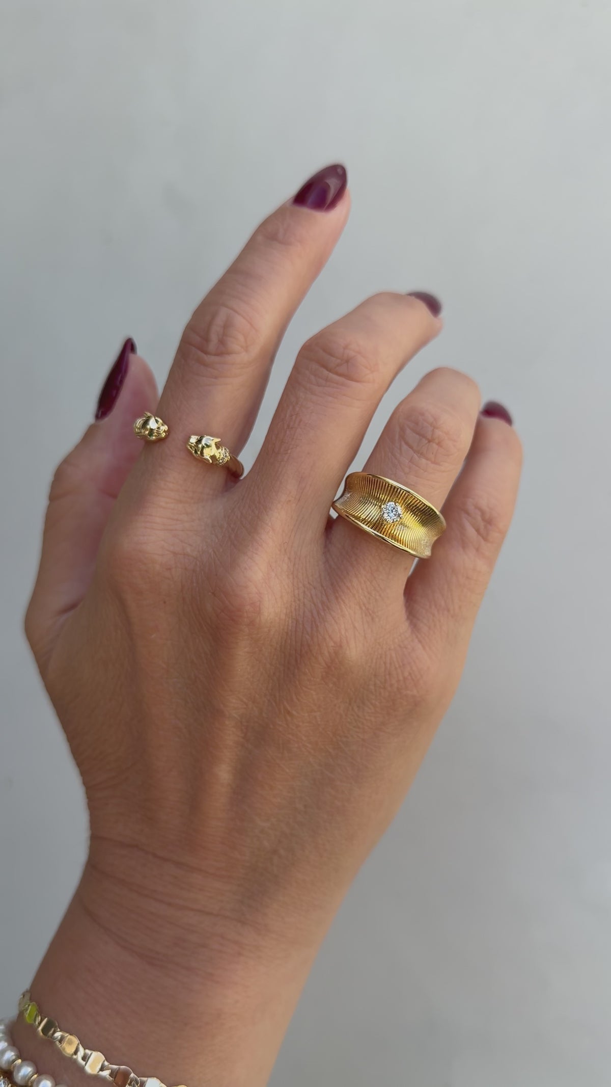 Image of a models hand wearing a beautiful ring stack, consisting of the gold panther ring and gold Anne-Marie ring. 