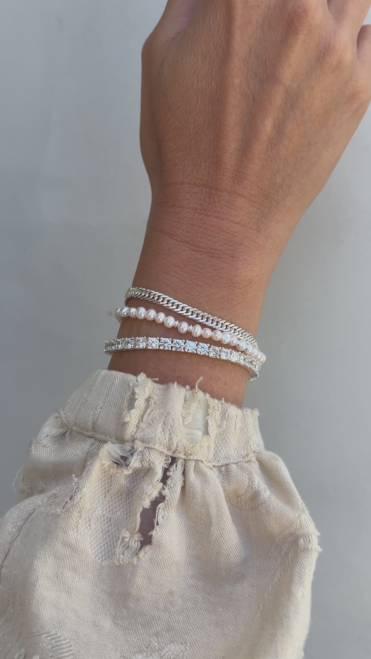 Model image of a wrist stack featuring the Blair, Bette and Audrey bracelets in silver set against a neutral background.